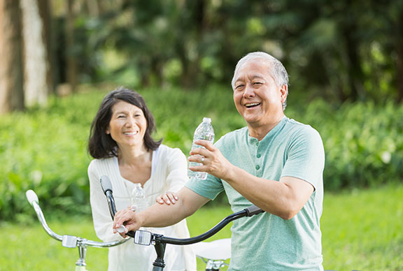 Asian seniors riding bikes with water bottles
