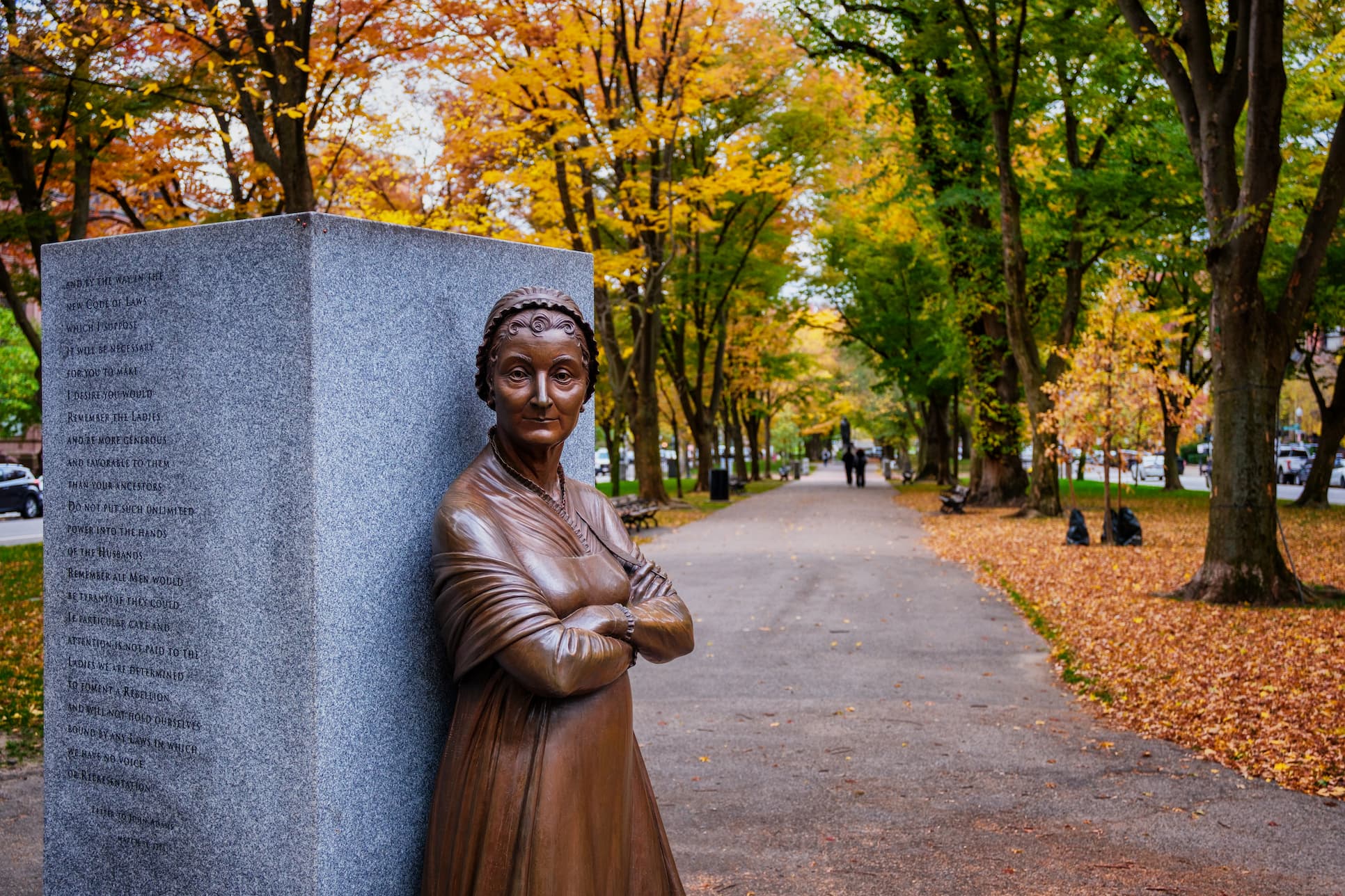 Statue of a woman in a park leaning on a large block with text inscribed